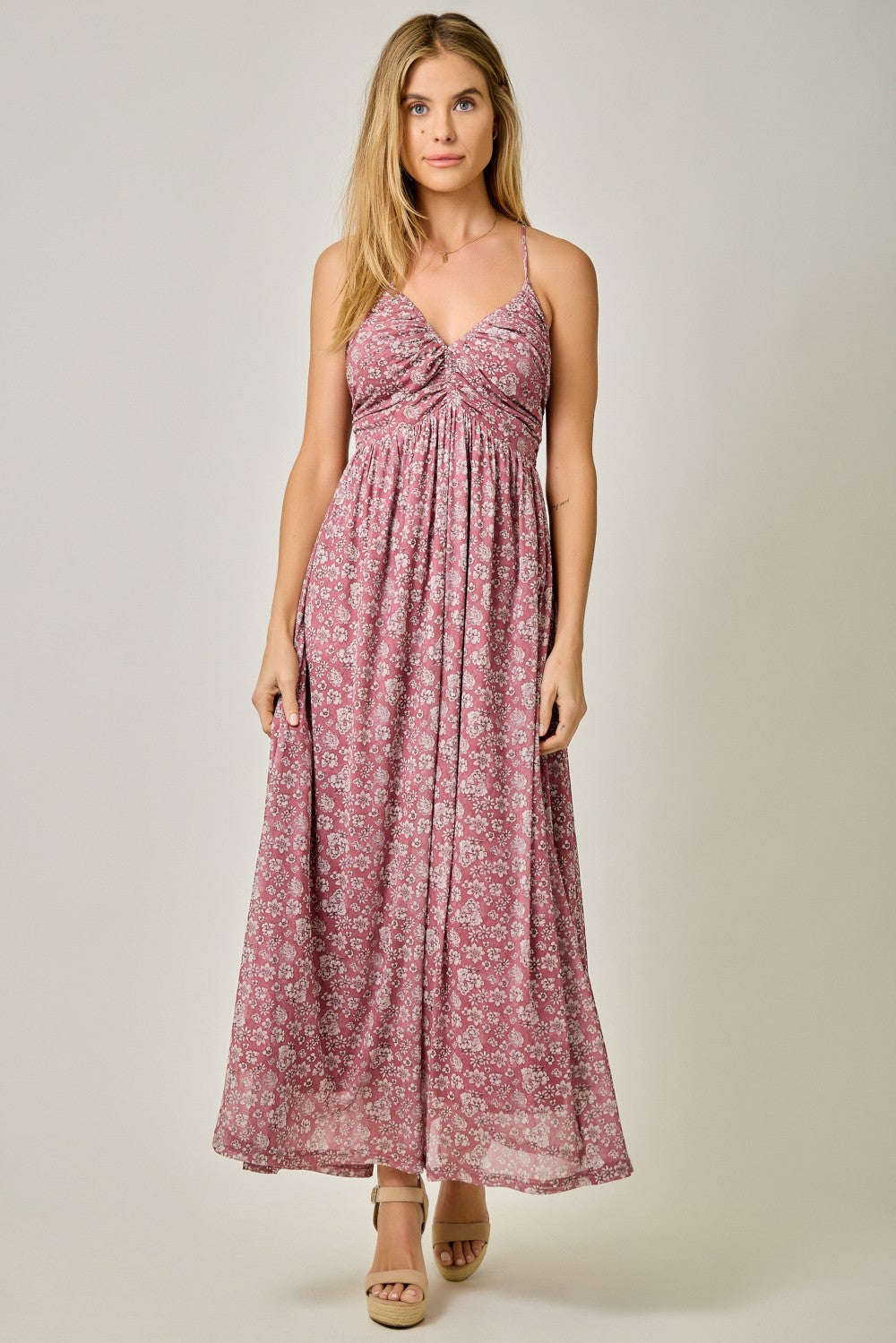 woman wearing a pink floral maxi dress with a twisted knot detail at the bust and spaghetti straps