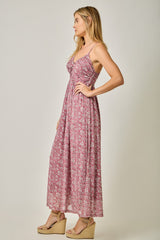 woman wearing a pink floral maxi dress with a gathered bodice and spaghetti straps, standing in profile on a light background