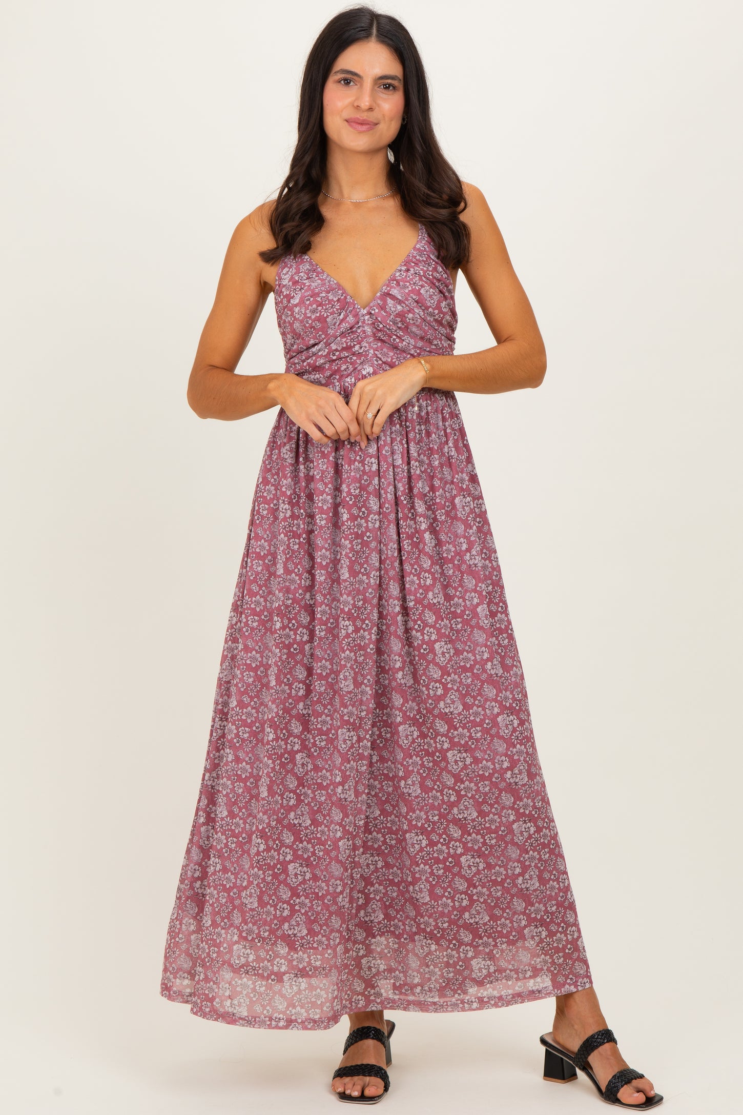 woman wearing a burgundy floral maxi dress with a v-neckline and thin straps, standing and smiling