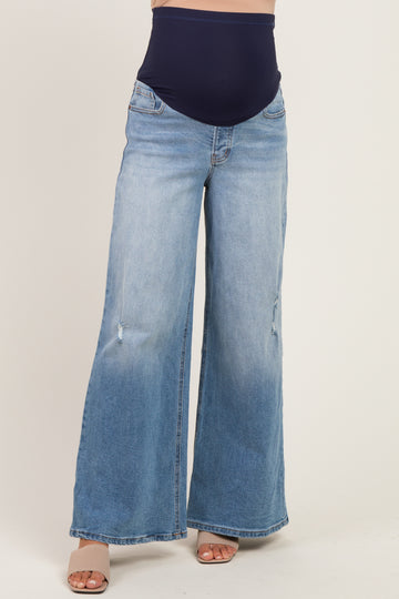 woman wearing light blue maternity wide-leg jeans with a dark blue over-the-bump waistband and distressed details