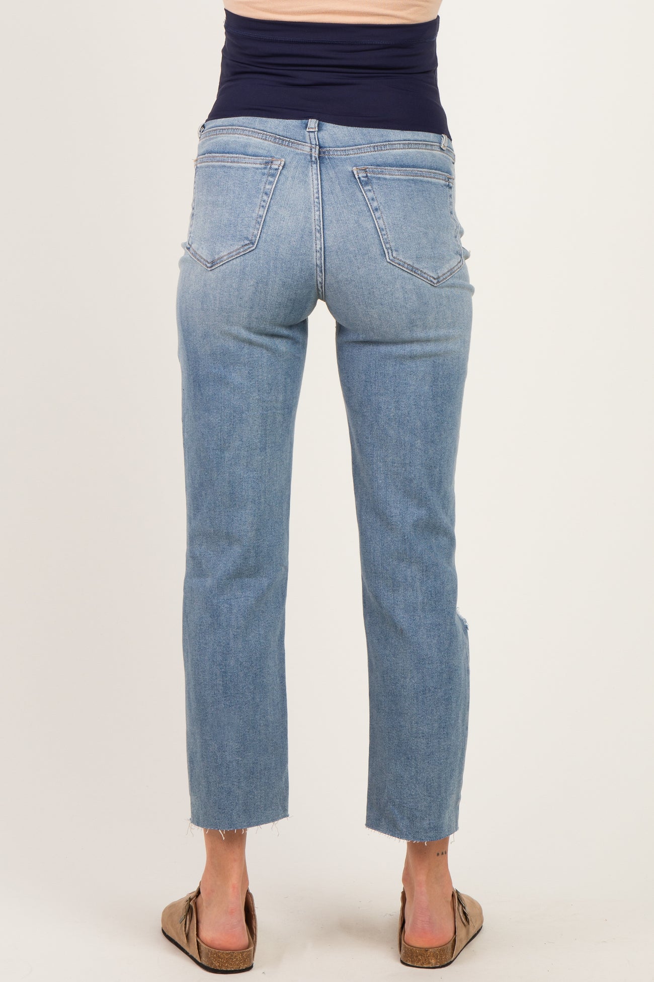 woman wearing light blue maternity jeans with a frayed hem, showing a fitted waistband and back view