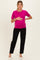 woman wearing a bright pink maternity top and black pants, holding her baby bump