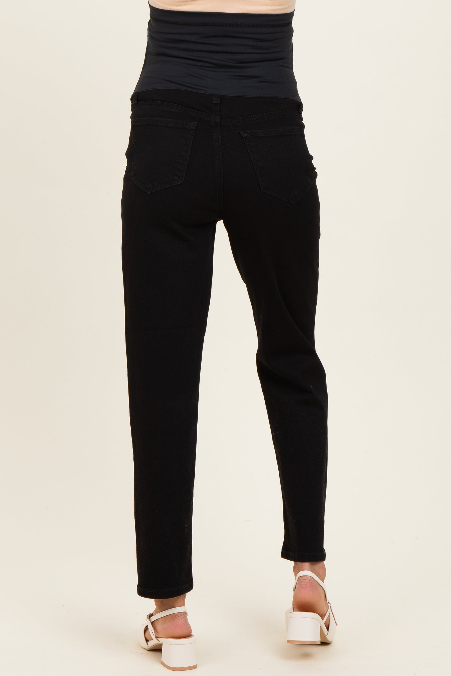 woman wearing black maternity jeans viewed from the back, featuring a stretchy waistband and slim fit