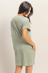 woman wearing a loose-fitting sage green t-shirt dress with short sleeves and side pockets