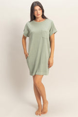 woman wearing a light green oversized t-shirt dress with a chest pocket and rolled sleeves