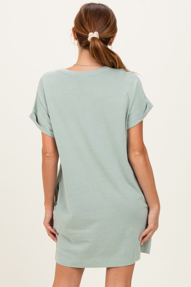 woman wearing a pale green short sleeve loose fit t-shirt dress, showing the back view
