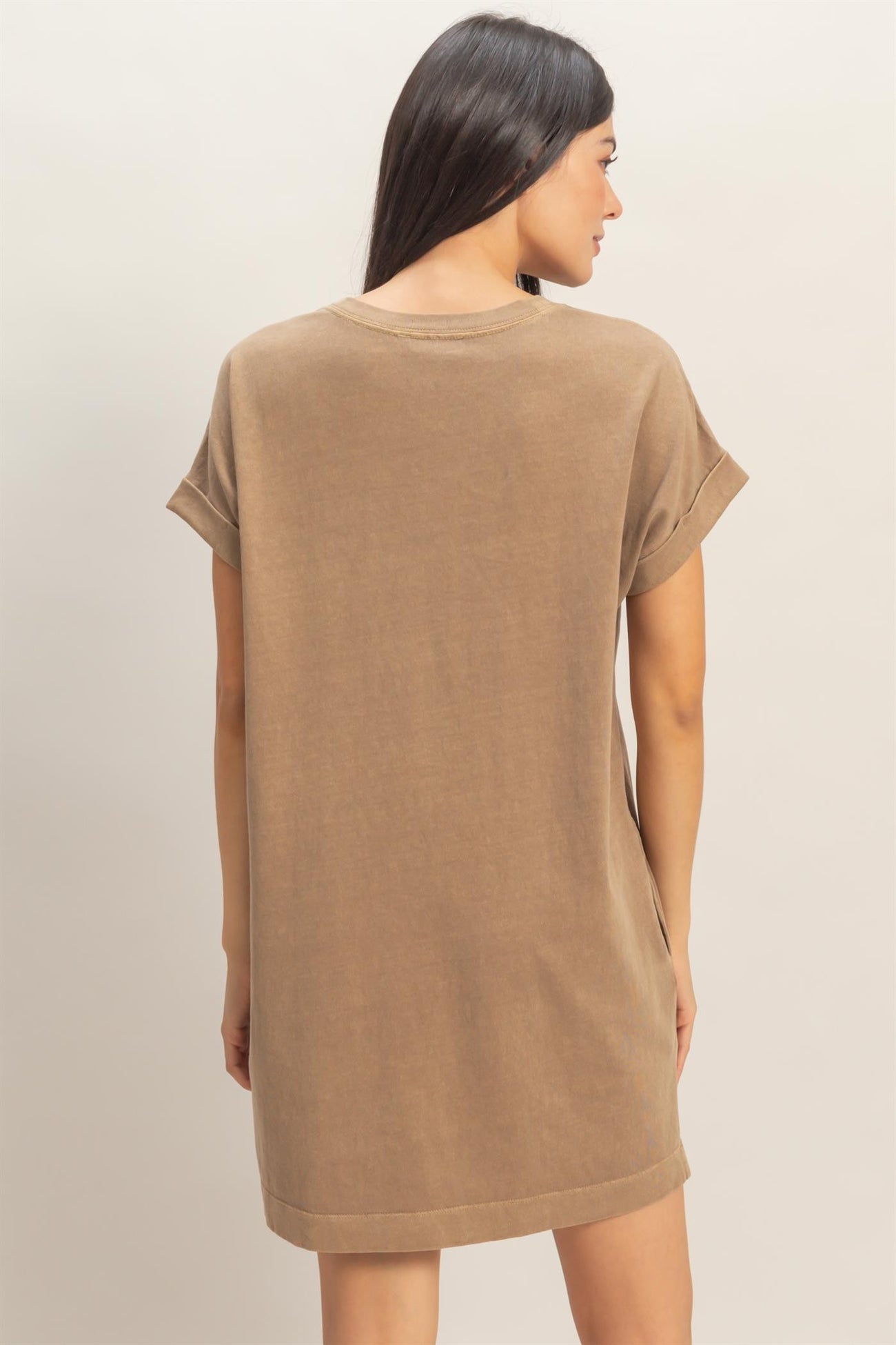woman wearing a brown oversized t-shirt dress with rolled sleeves, showing the back view