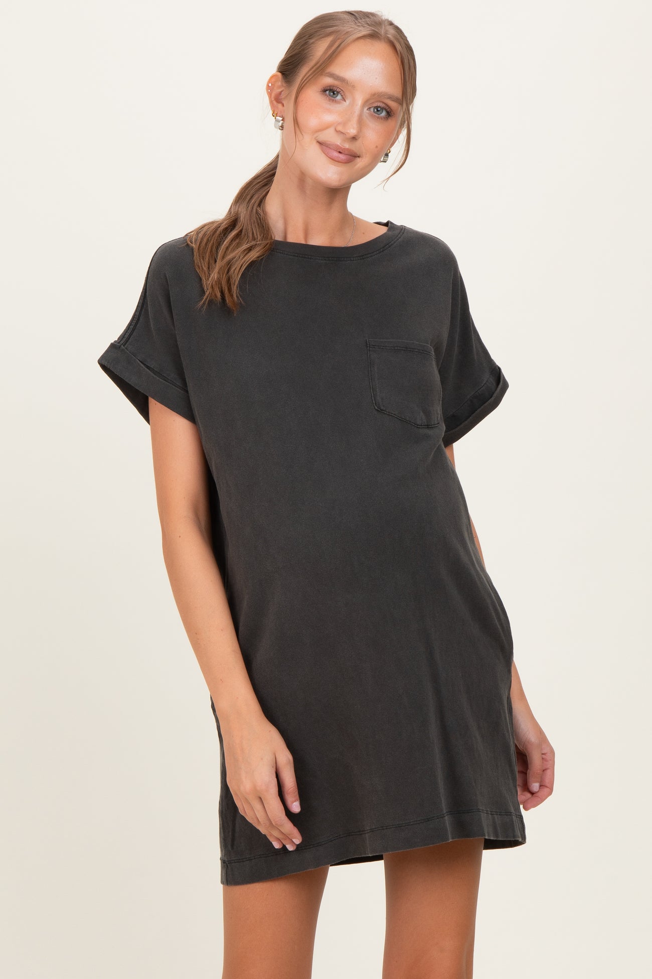 woman wearing a black short sleeve maternity dress with a front pocket and a relaxed fit, showing her baby bump