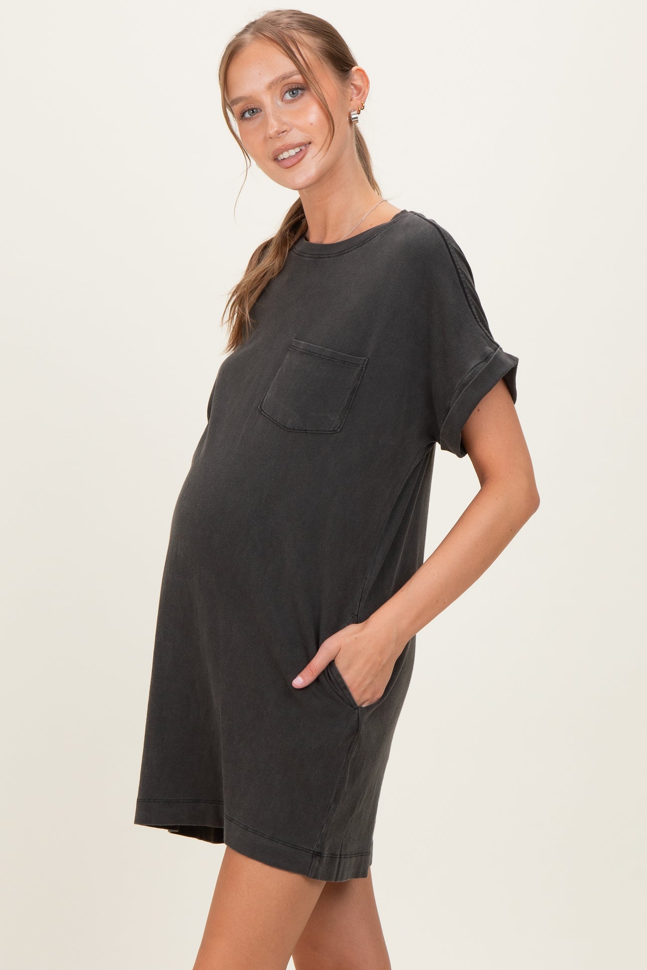 woman wearing a dark gray short sleeve maternity dress with a pocket and a visible baby bump