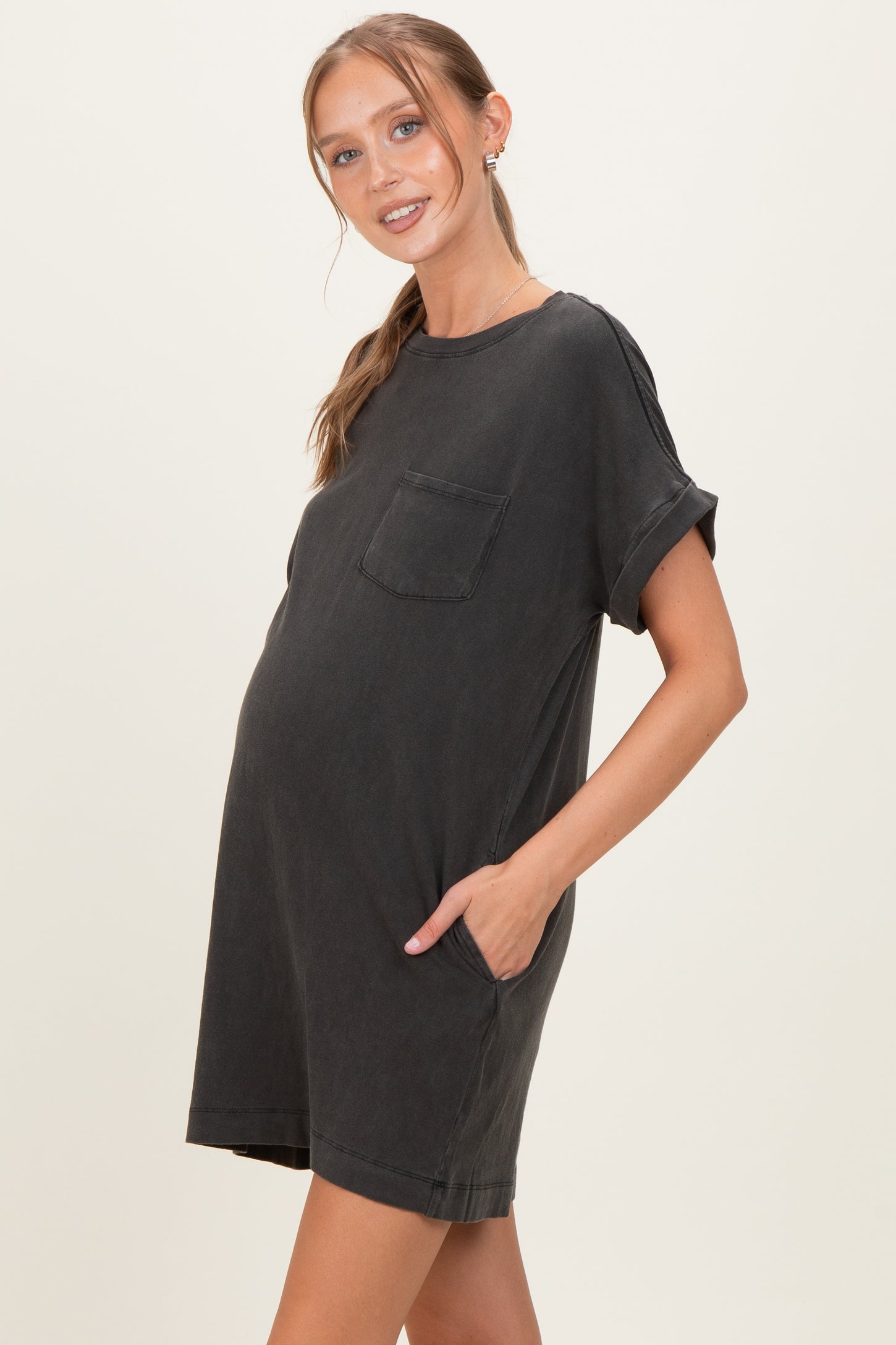woman wearing a dark gray short sleeve maternity dress with a pocket and a visible baby bump
