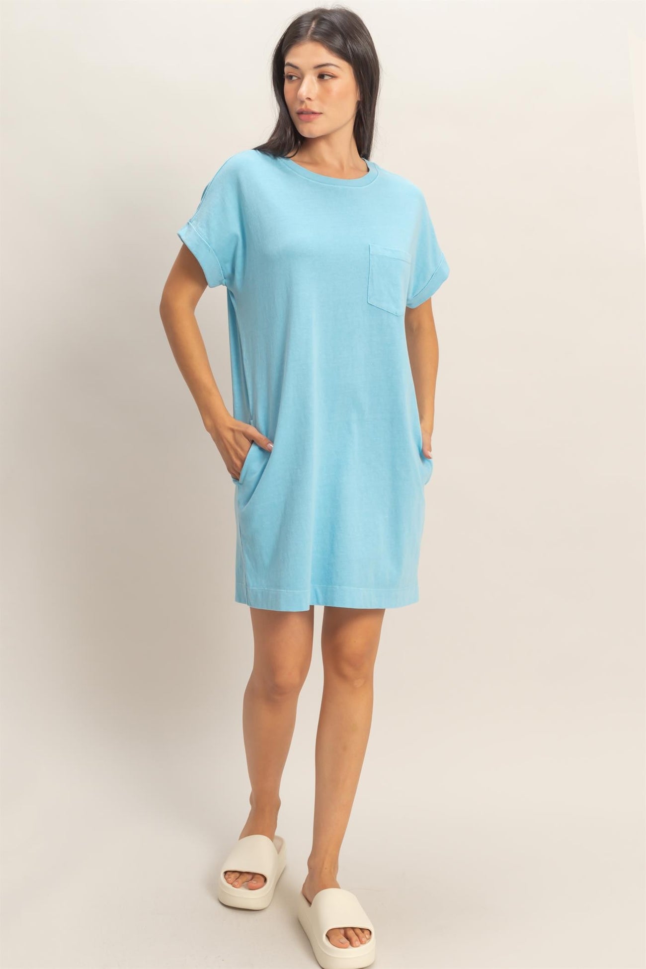 woman wearing a light blue short sleeve pocket dress with side pockets and white slide sandals