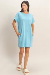 woman wearing a light blue short sleeve pocket dress with side pockets and white slide sandals