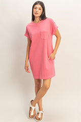 woman wearing a pink short sleeve t-shirt dress with a pocket and side pockets, standing in a relaxed pose