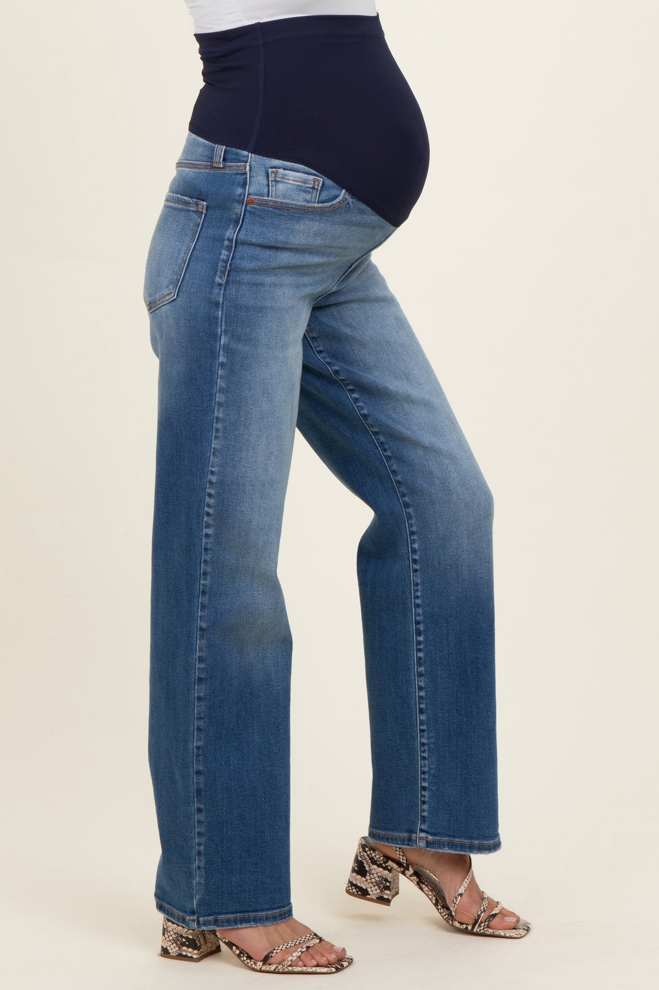 woman wearing a pair of blue straight-leg maternity jeans with a supportive waistband and a visible baby bump
