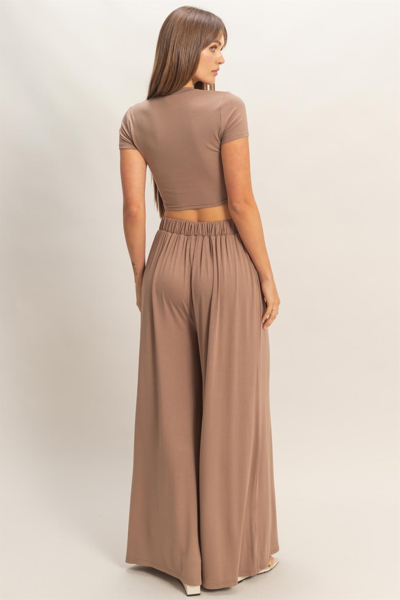 woman wearing a taupe crop top and matching wide-leg pants, showing the back view and waistband details