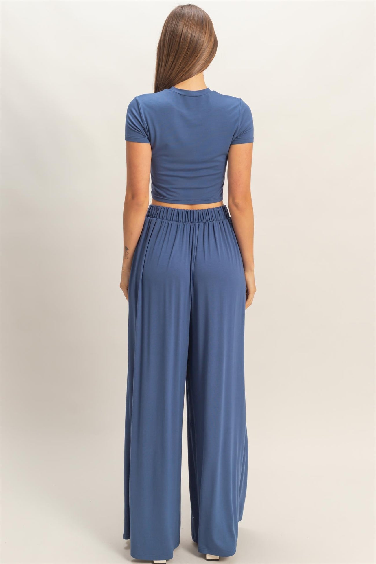 woman wearing a blue cropped t-shirt and matching wide-leg pants, viewed from the back