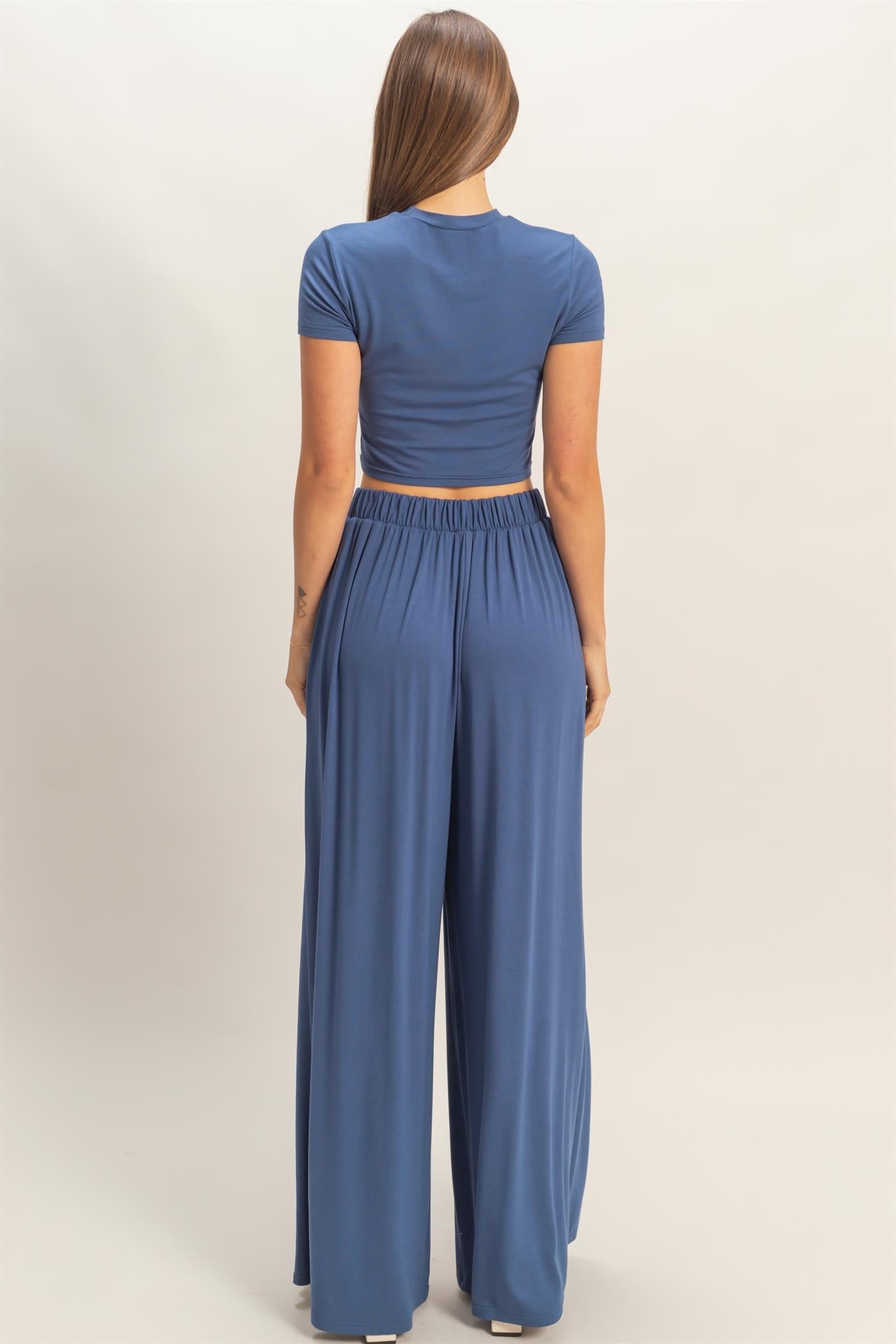woman wearing a blue cropped t-shirt and matching wide-leg pants, viewed from the back