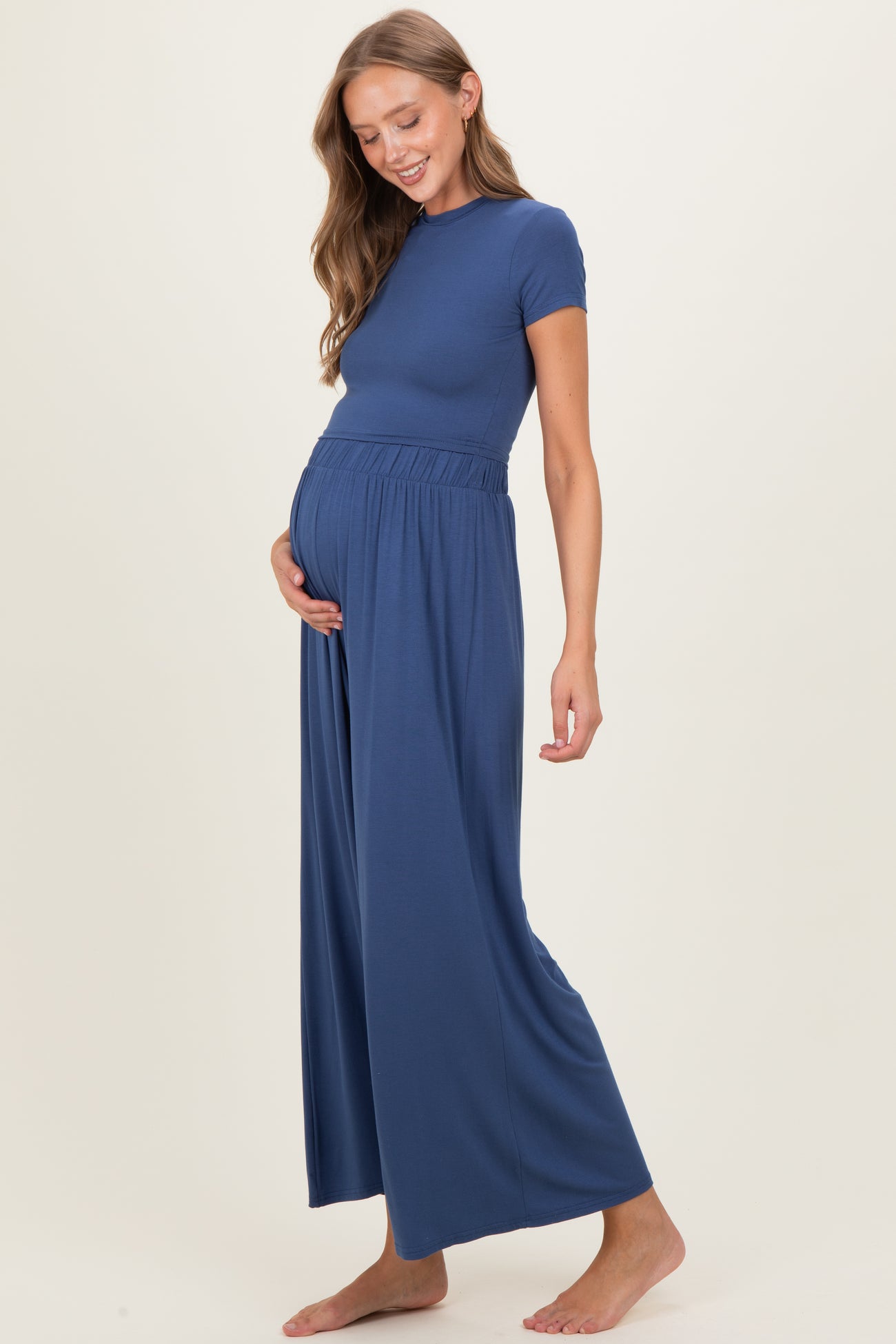 woman wearing a navy blue maternity jumpsuit with a fitted top and wide-leg pants, showing her baby bump