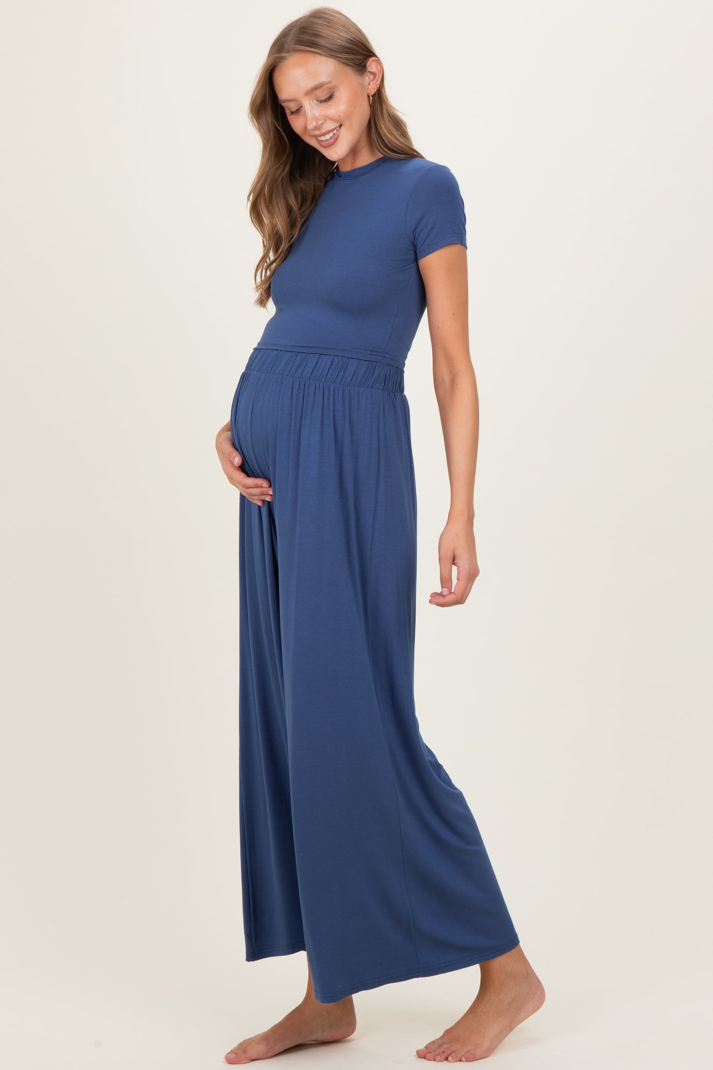 woman wearing a navy blue maternity jumpsuit with a fitted top and wide-leg pants, showing her baby bump
