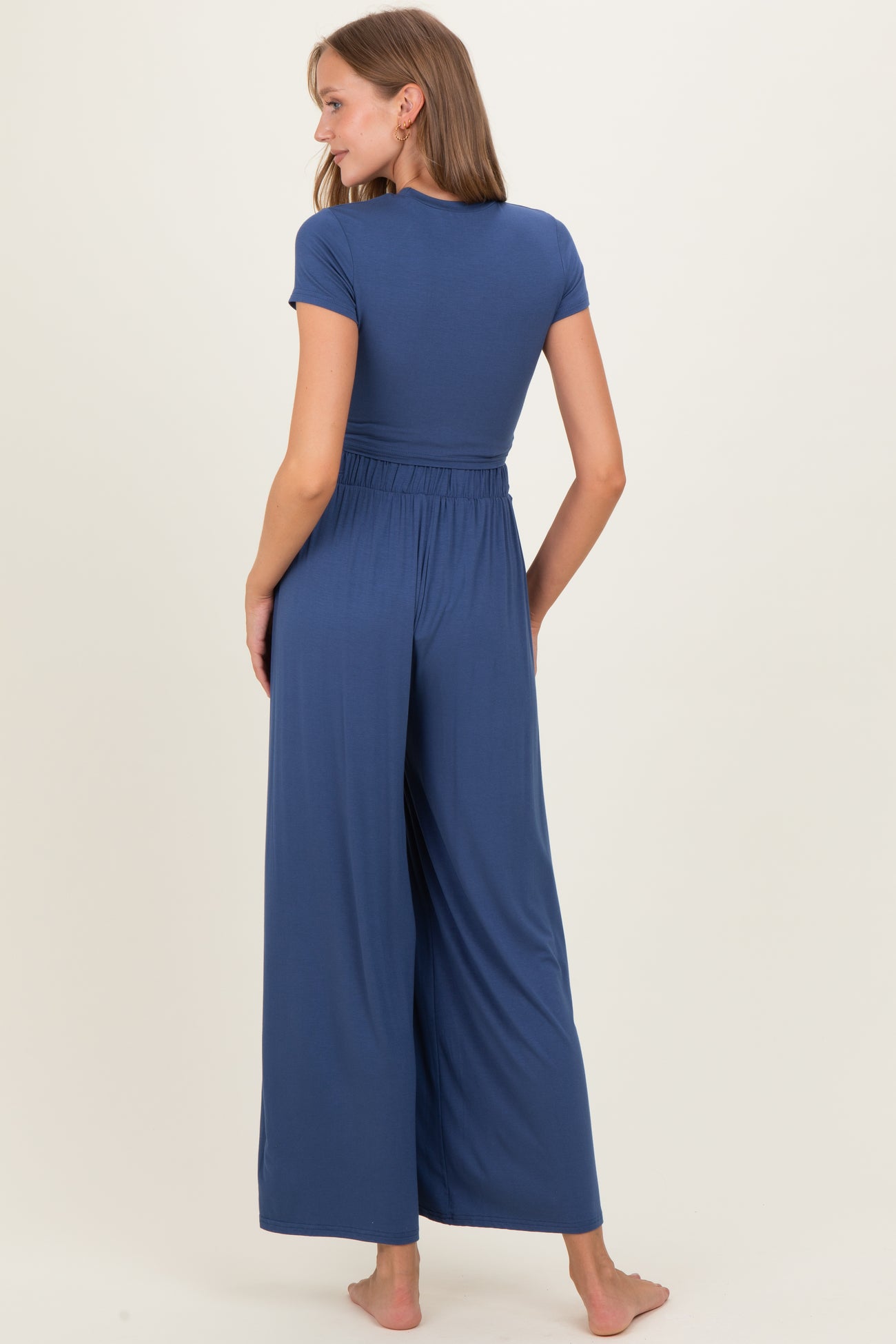 woman wearing a navy blue maternity jumpsuit with short sleeves and wide leg pants, showing a relaxed fit from the back