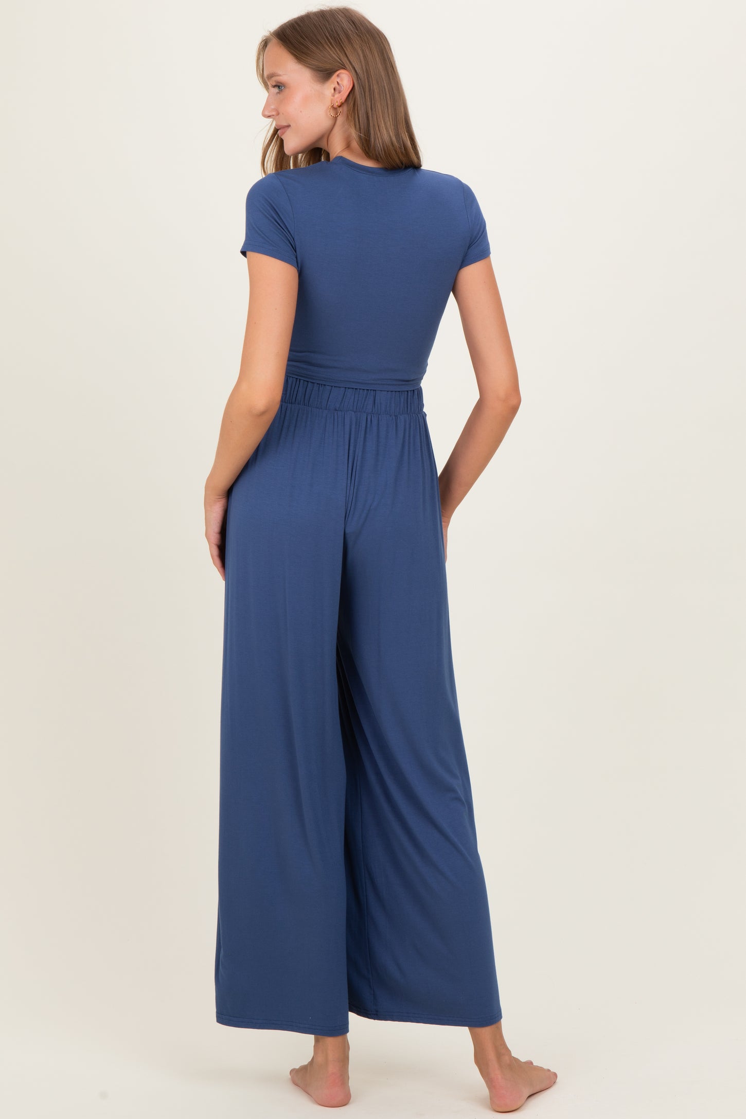 woman wearing a navy blue maternity jumpsuit with short sleeves and wide leg pants, showing a relaxed fit from the back
