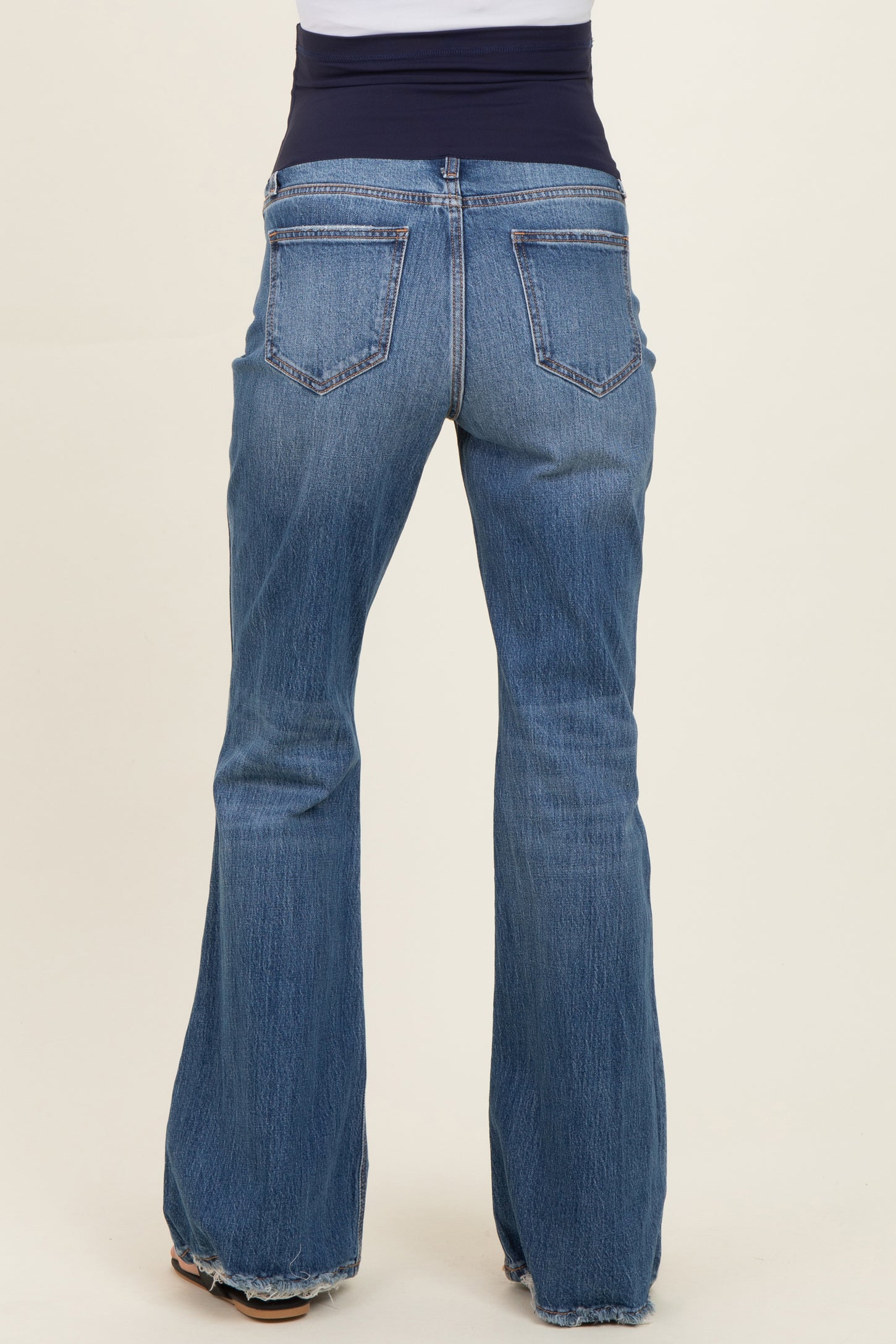 maternity wear flared blue jeans with a dark blue elastic waistband, worn by a model from the back