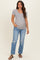 woman wearing a navy and white striped maternity t-shirt with a scoop neckline and pocket, paired with distressed blue jeans