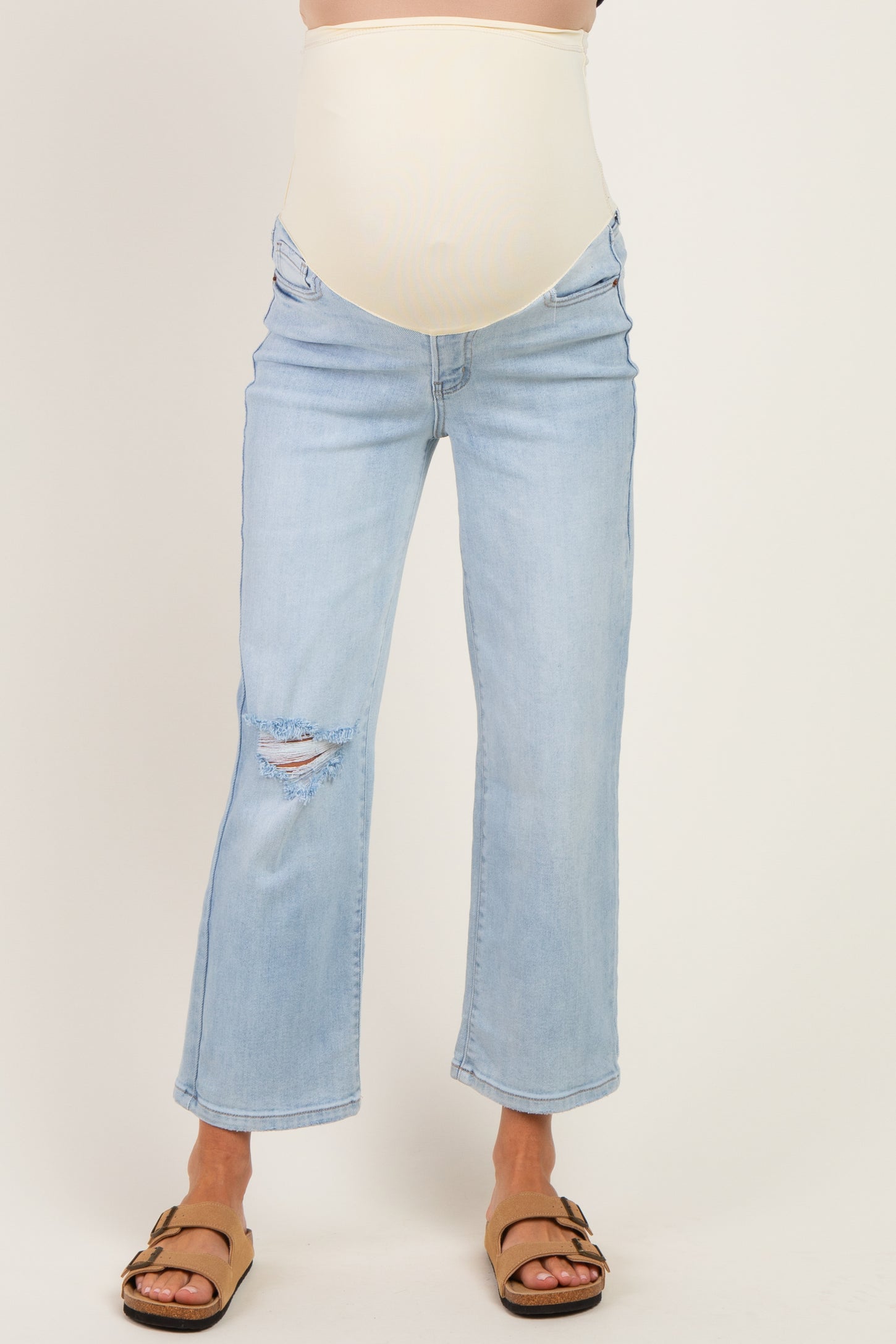 woman wearing light blue maternity jeans with a fitted belly panel and distressed details