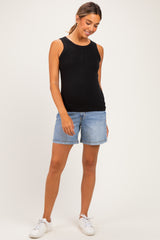 woman wearing a black maternity tank top and denim shorts, with a visible baby bump