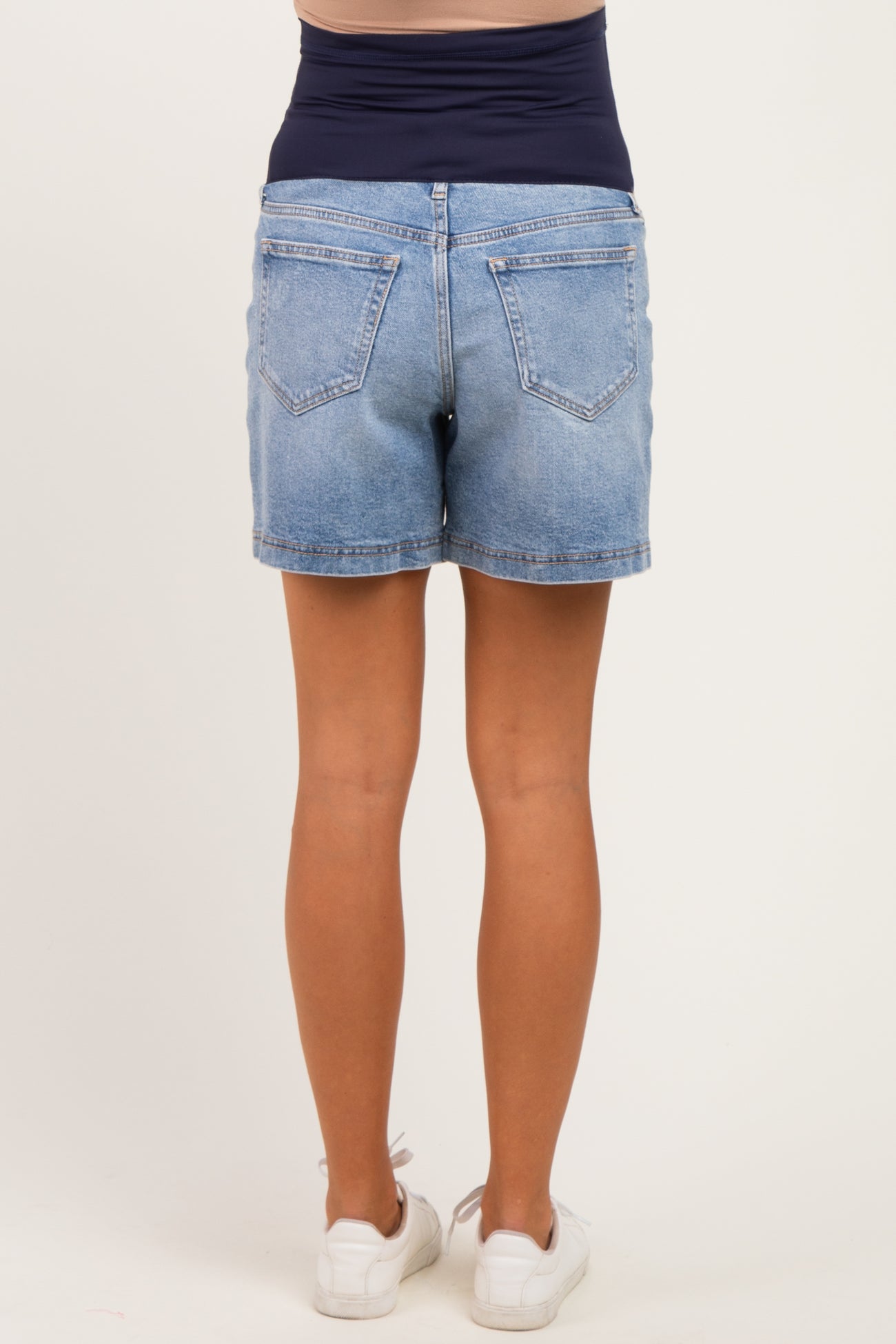 woman wearing light wash maternity shorts with a stretchy navy waistband, viewed from the back