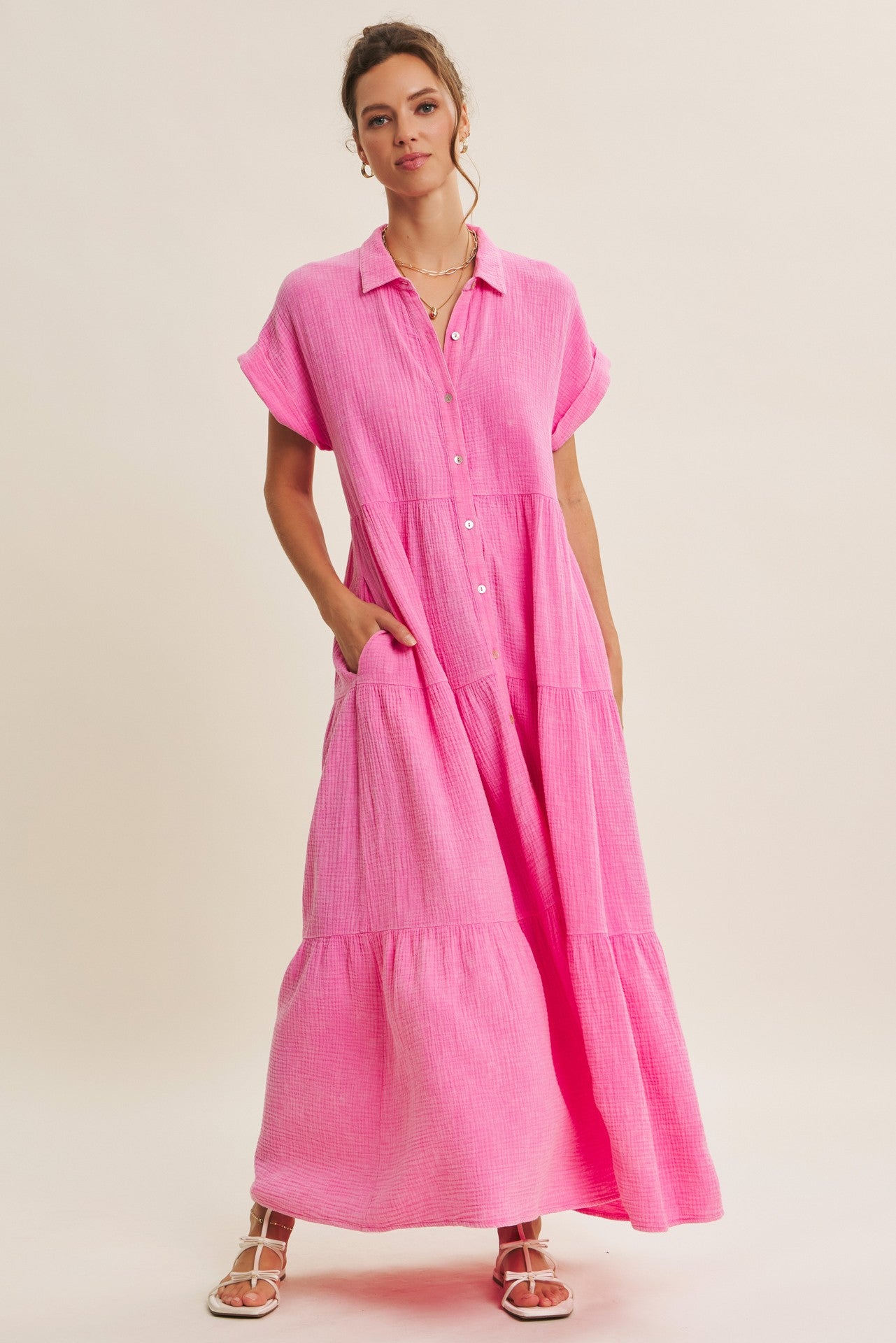 woman wearing a bright pink collared maxi dress with short sleeves and pockets, styled in a relaxed fit