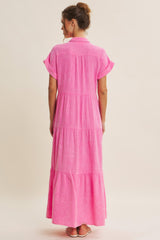 woman wearing a bright pink maxi dress with short sleeves and a tiered design, viewed from the back
