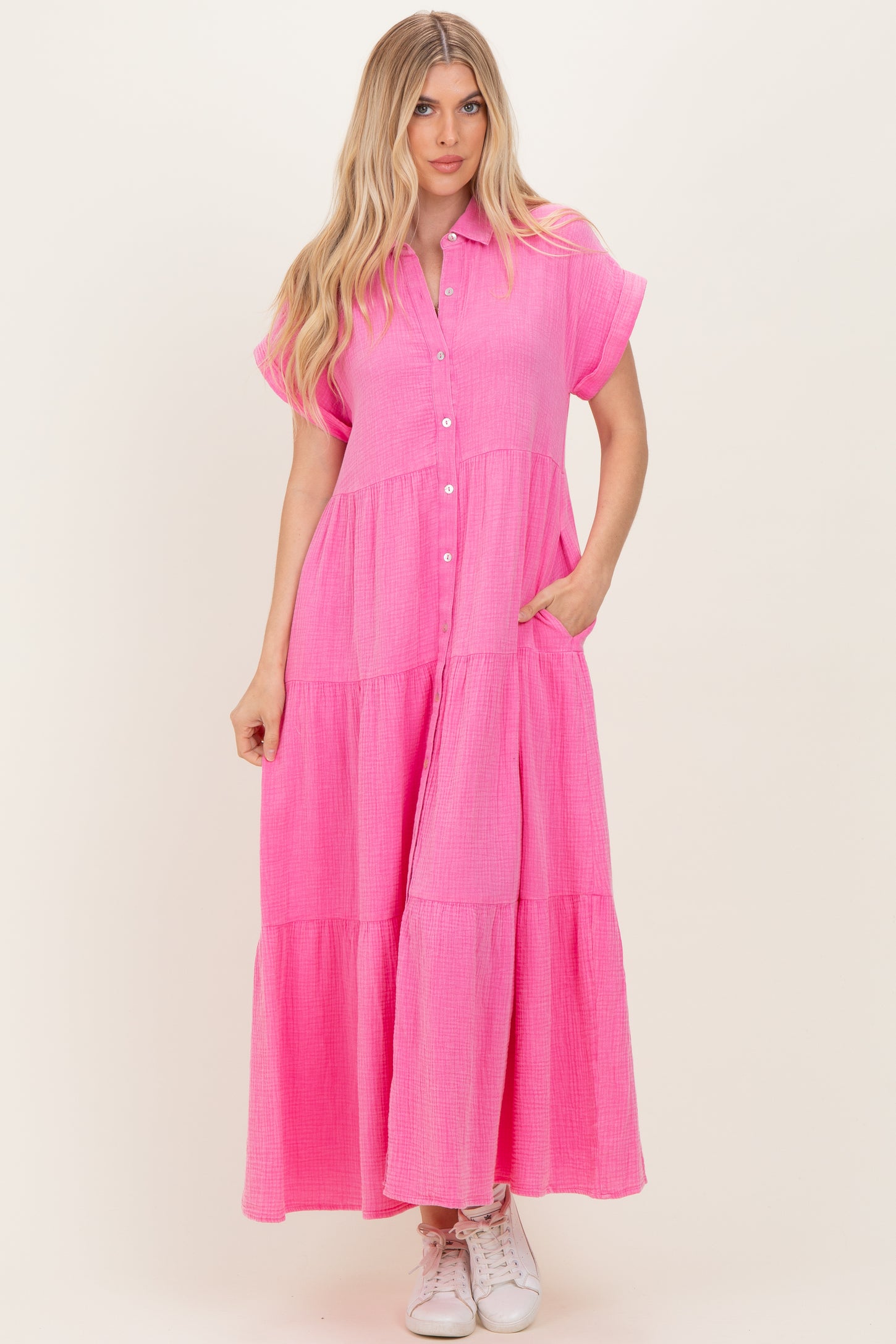 woman wearing a bright pink button-up maxi dress with short sleeves and tiered skirt detail