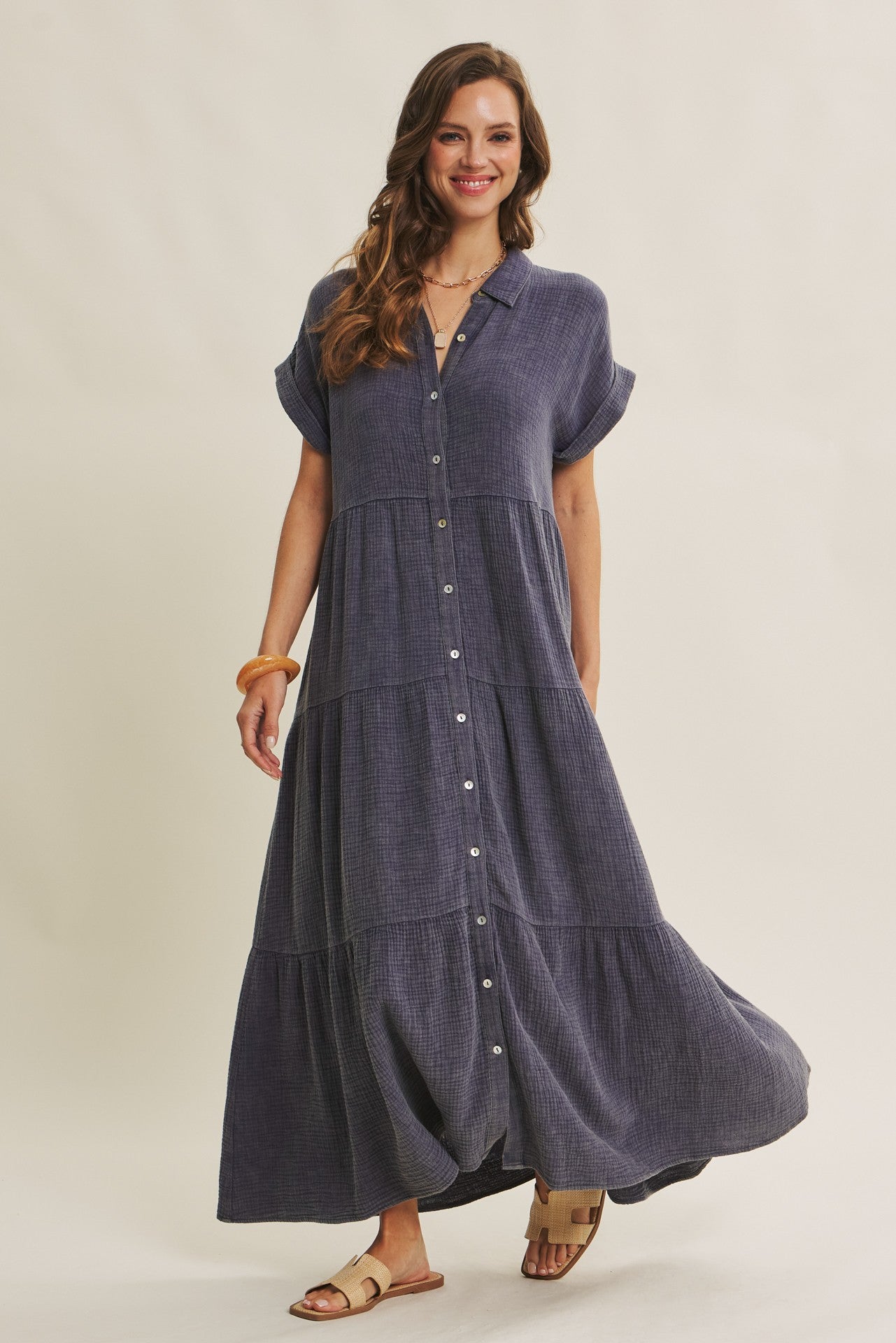 woman wearing a navy blue tiered maxi dress with short sleeves and buttons down the front