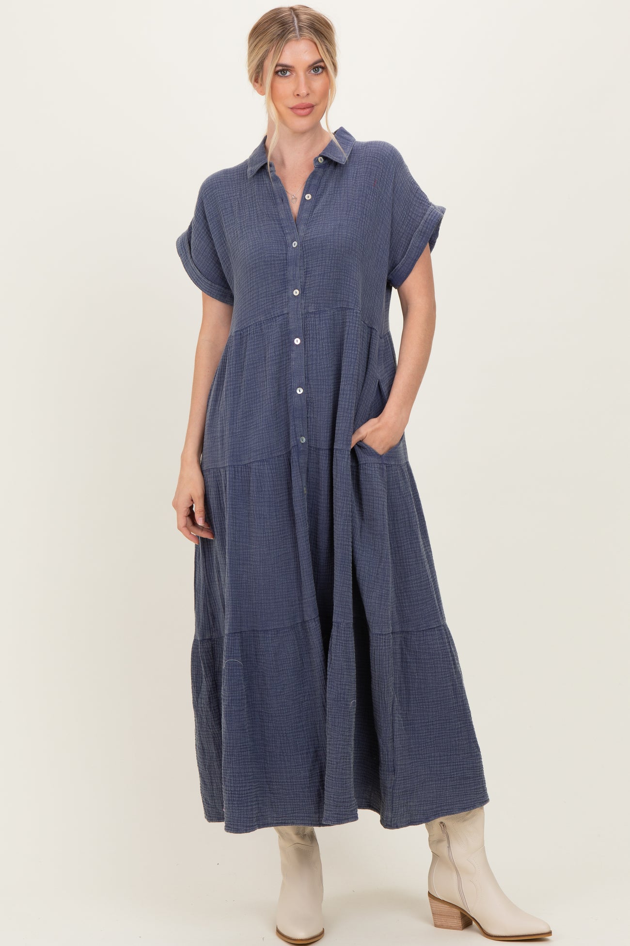woman wearing a navy blue button-up shirt dress with short sleeves and pockets, styled with cream-colored boots