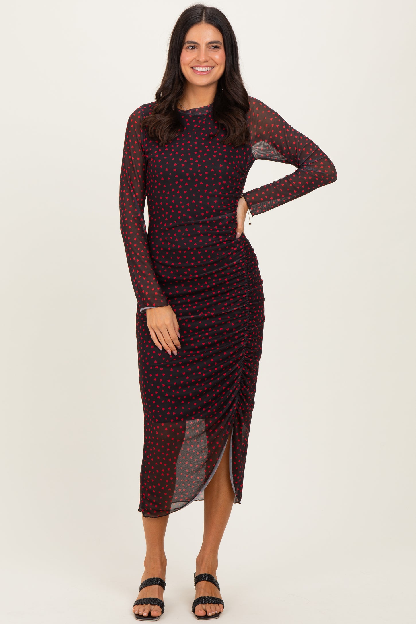 woman wearing a black and red polka dot long sleeve dress with ruching and a side slit