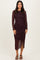 woman wearing a black and red polka dot long sleeve dress with ruched side details and a midi length