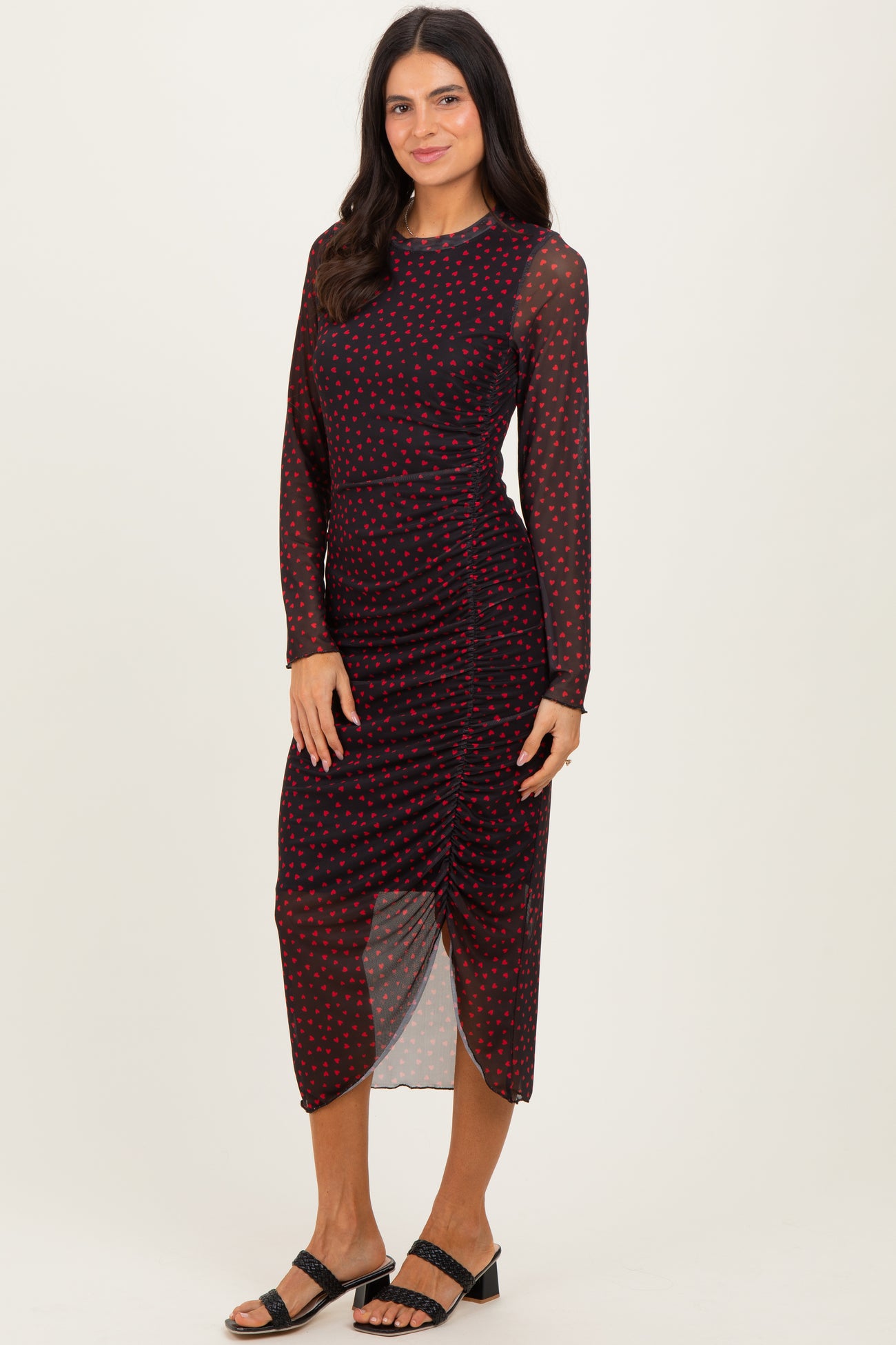 woman wearing a burgundy polka dot long sleeve midi dress with ruching detail and a high slit