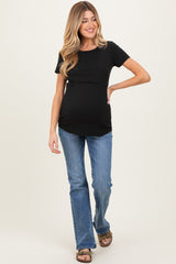 woman wearing a black short sleeve maternity top and blue flared jeans, showing her baby bump