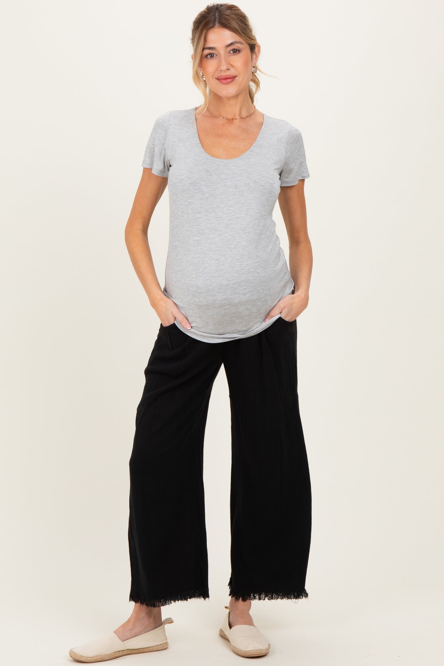 woman wearing a gray maternity t-shirt and black wide-leg maternity pants, showing her baby bump