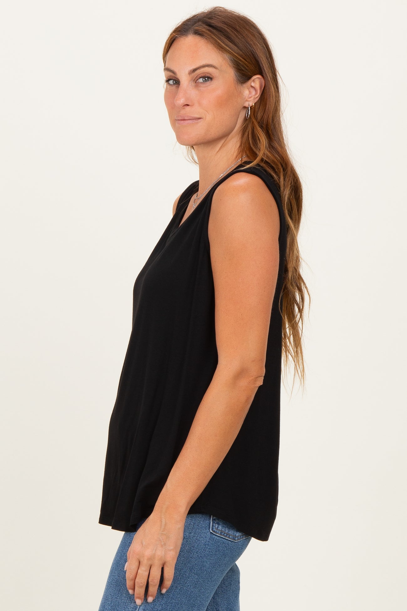 woman wearing a black sleeveless top with a relaxed fit and side slits paired with blue jeans