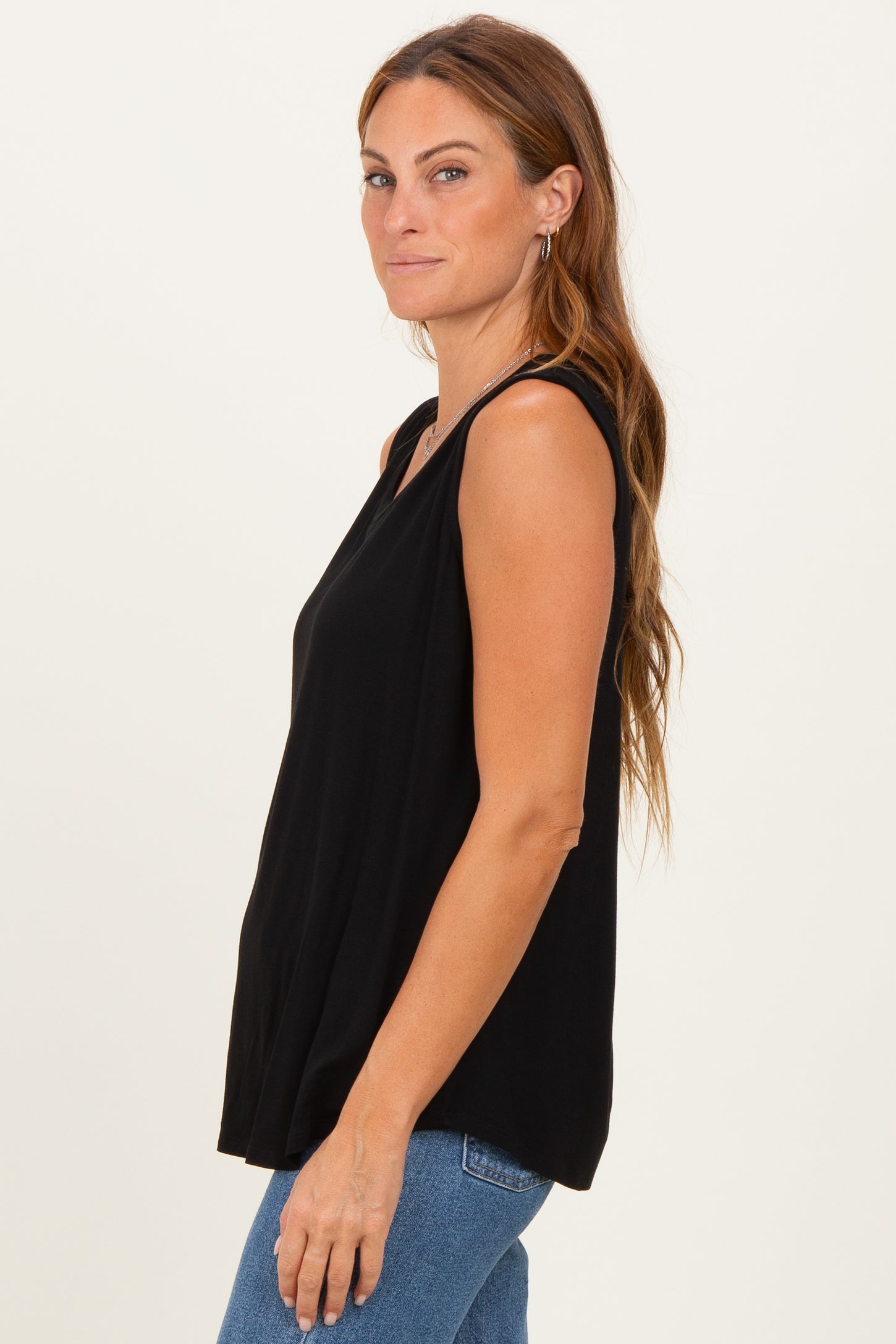 woman wearing a black sleeveless top with a relaxed fit and side slits paired with blue jeans