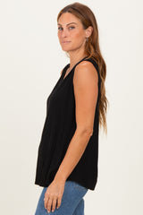 woman wearing a black sleeveless top with a relaxed fit and side slits paired with blue jeans