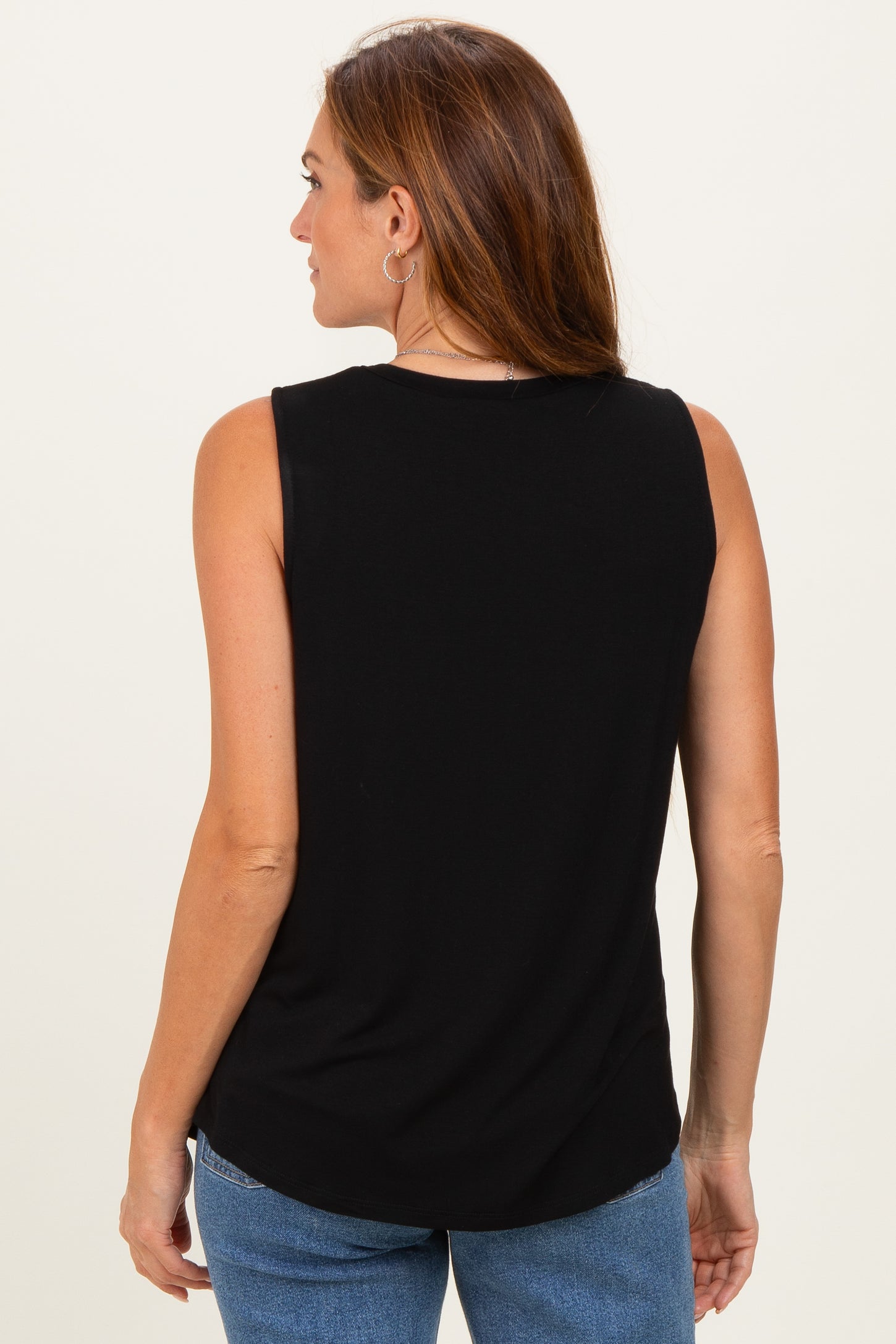 woman wearing a black sleeveless top, with a rounded hem and casual fit, seen from the back