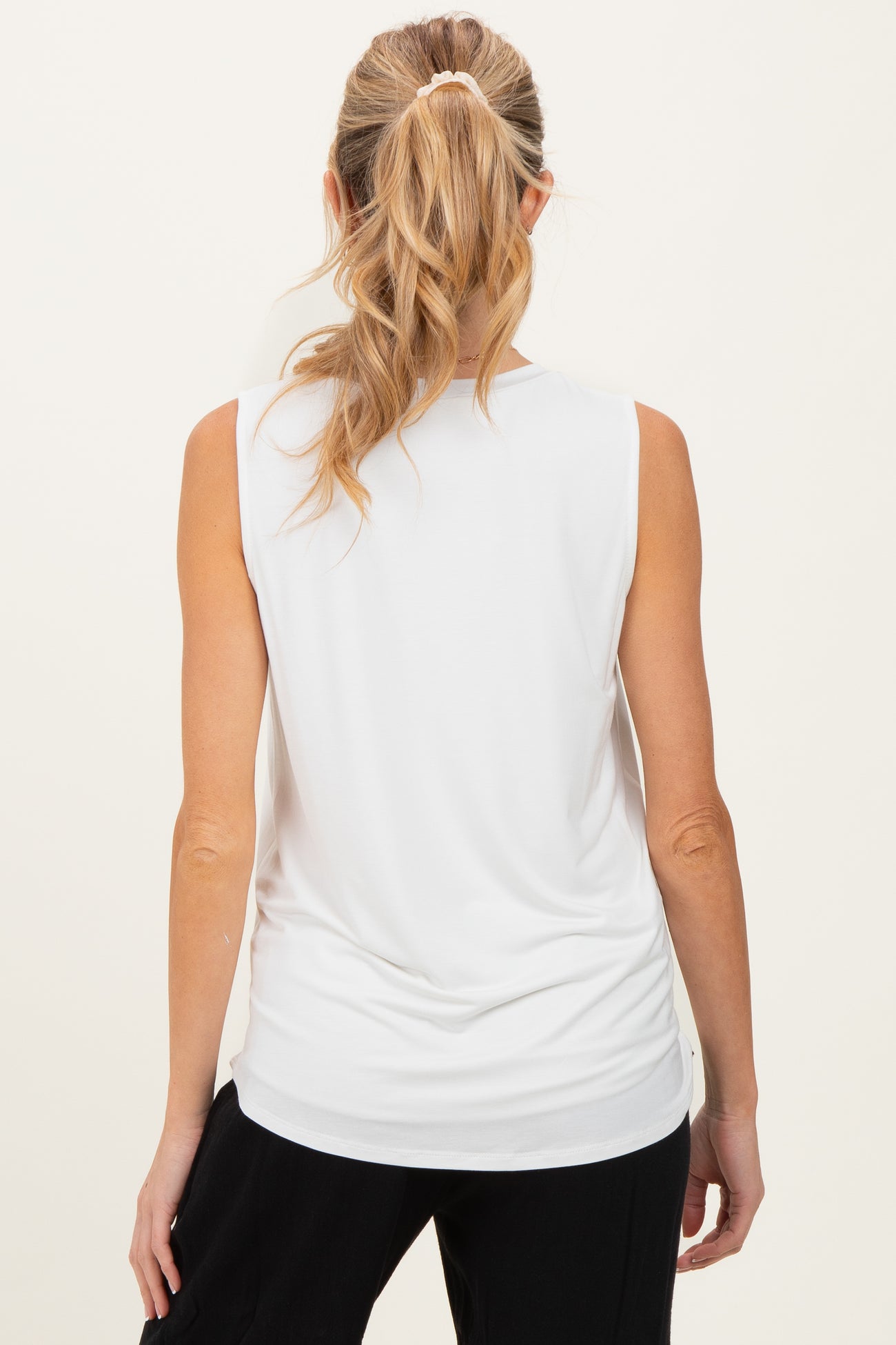 woman wearing a white sleeveless maternity top, shown from the back