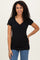woman wearing a black short sleeve top with a ruched v-neck and standing with one hand on her hip