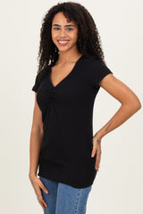 woman wearing a black short sleeve ribbed top with a twist detail at the neckline and paired with denim jeans