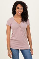woman wearing a light mauve short sleeve ribbed top with a v-neck and gathering detail at the front