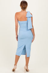 woman wearing a light blue one-shoulder bodycon dress with a bow detail and a slit at the back
