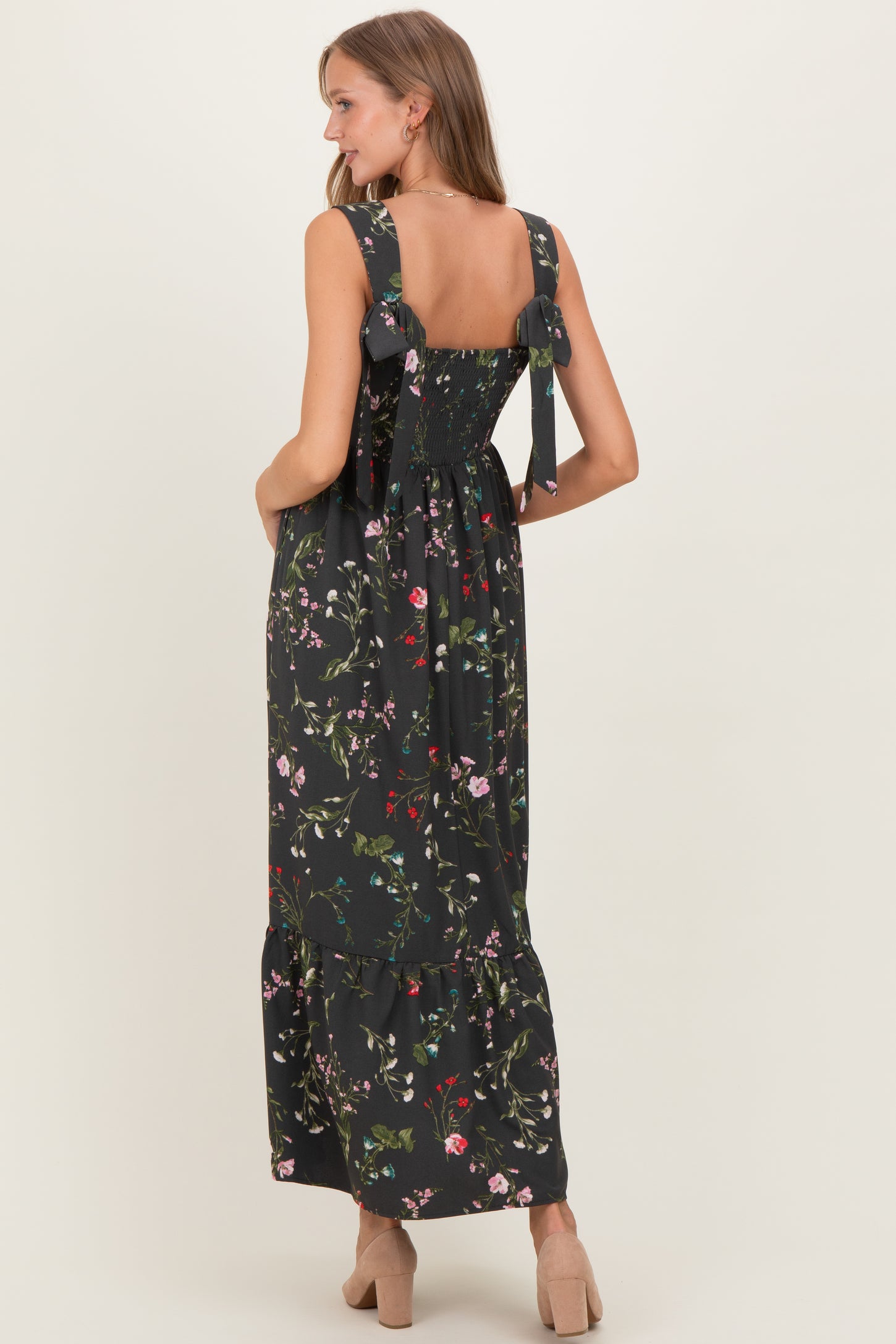 woman wearing a black floral print maternity dress with ruffled straps and a tiered skirt, showing her pregnant belly